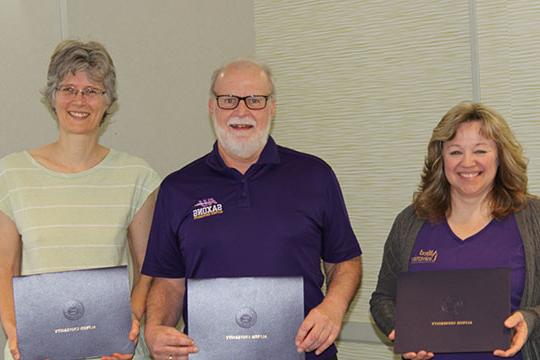 three people holding certificates