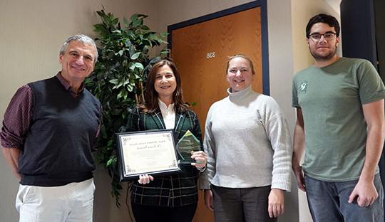 photo of four people, two men, two women, one holding an award plaque