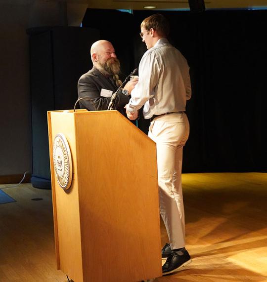 two men shaking hands at a podium