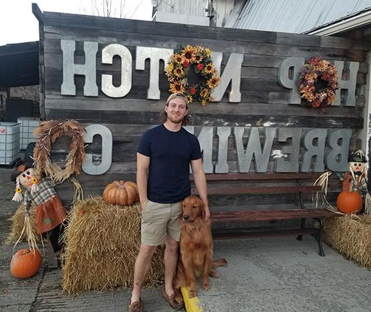 man with hat on standing next to dog