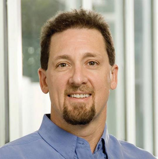 headshot of man in blue shirt, goatee