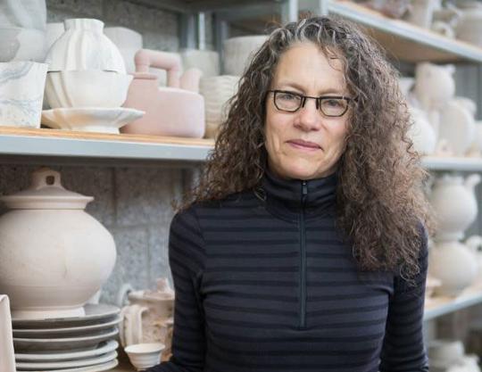 headshot of woman with glasses in front of pottery